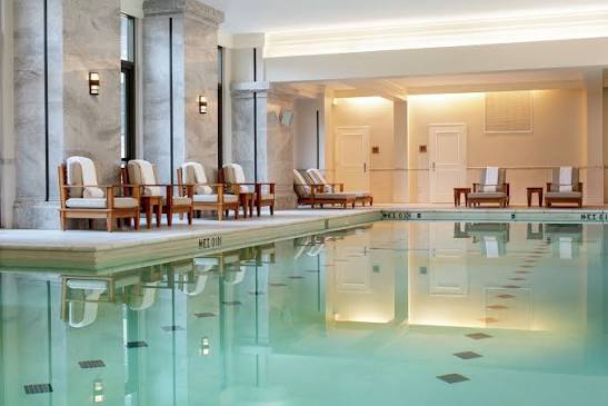 Indoor hotel spa pool with lounge chairs and marble columns